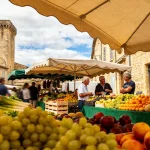 Marché coloré avec fruits frais devant une tour médiévale à Brignoles Provence