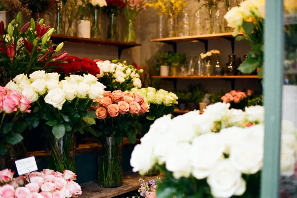Bouquets de roses colorées dans la boutique Les Belles Fleuristes sur des étagères en bois
