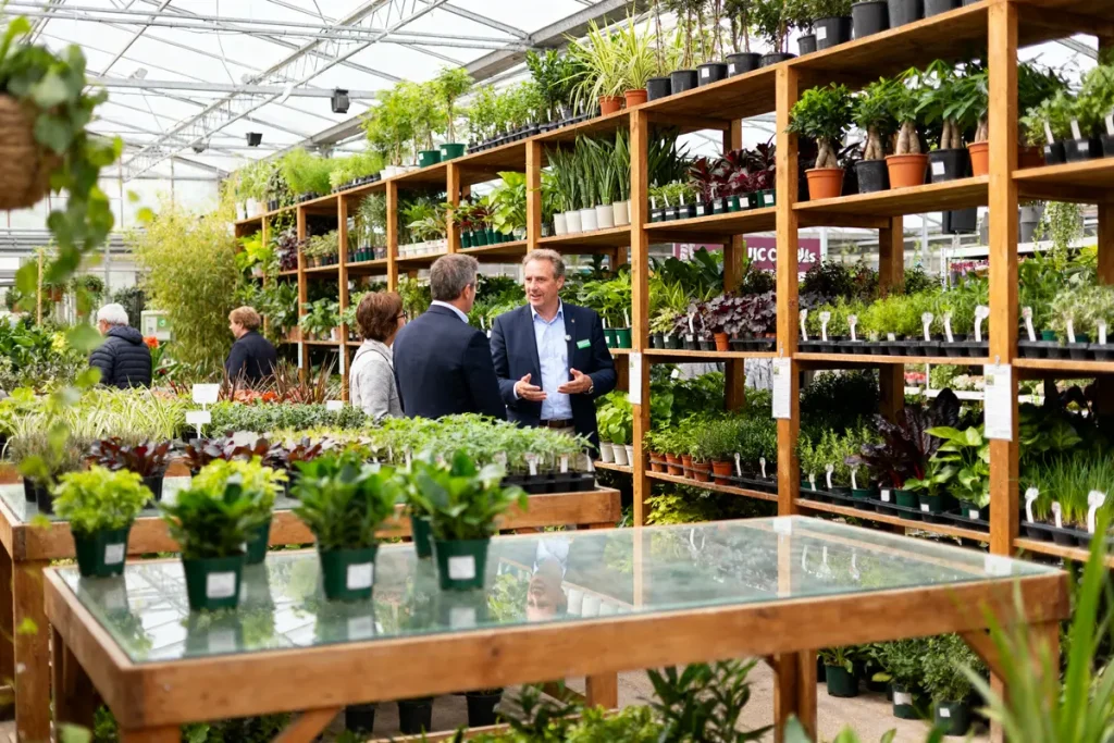 Personnes discutant parmi les plantes de la Jardinerie d'Ici Chelles pendant une visite