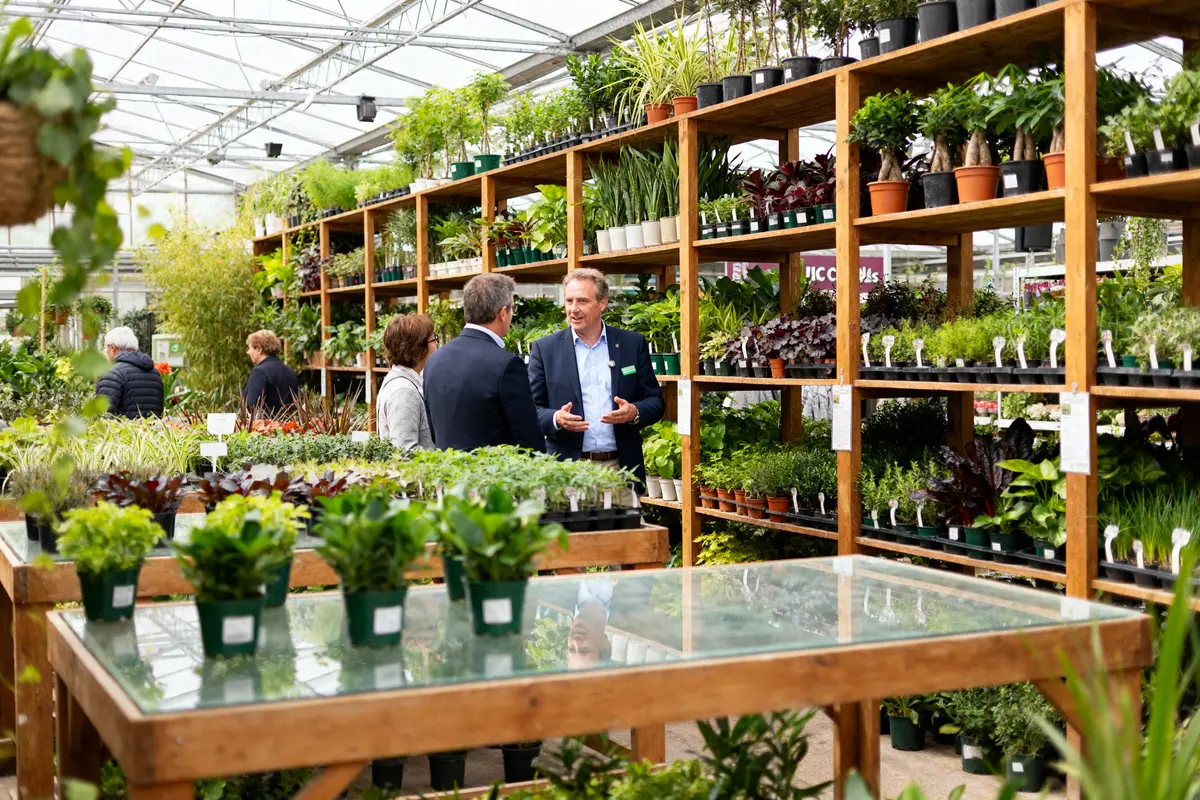Personnes discutant parmi les plantes de la Jardinerie d'Ici Chelles pendant une visite
